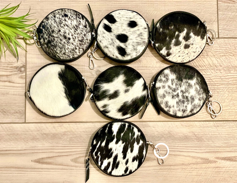 May include: Seven round black and white cowhide coin purses with silver keychains.