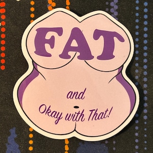 May include: Purple and white sticker with the text "FAT and Okay with That!" in a stylized font. The sticker is shaped like a body with a large bust and a round belly.