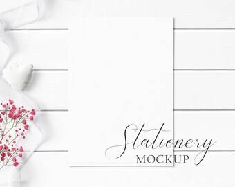 5x7 Stationery Mockup Styled with textured paper, red flowers, white ribbon, and white heart pillow on a white wood background.