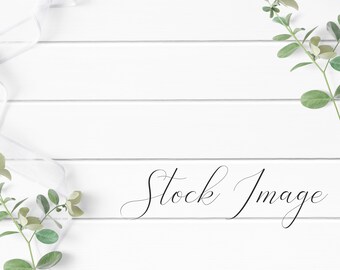 Feminine Flat Lay Styled with greenery and white ribbon on a white wood background.
