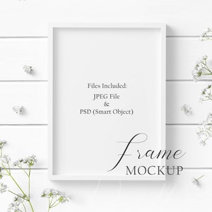May include: A white rectangular frame mockup with the text "Files Included: JPEG File & PSD (Smart Object)" and "frame MOCKUP". The frame is surrounded by white flowers and rests on a white wooden surface.