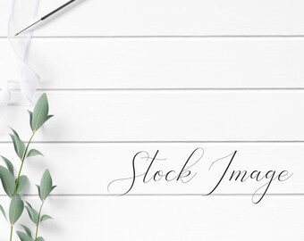 Feminine Flat Lay Styled with greenery, white ribbon, and white wood pencil on a white wood background.