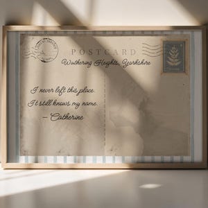 May include: Framed vintage postcard print with the text "Wuthering Heights, Yorkshire." The postcard features a stamp and postmark, with the quote "I never left this place. It still knows my name. - Catherine."