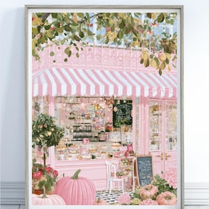 May include: A framed art print depicting a pink cafe storefront with a white and pink striped awning. The scene features large pink pumpkins in the foreground, a white chair, a chalkboard menu, and a display of pastries inside the glass window.