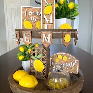 May include: A tiered wooden tray decorated with a lemon theme. The tray features signs that say "Lemons - $5-" and "Welcome". There are also small lemon-shaped decorations and a glass cloche with lemon slices inside.