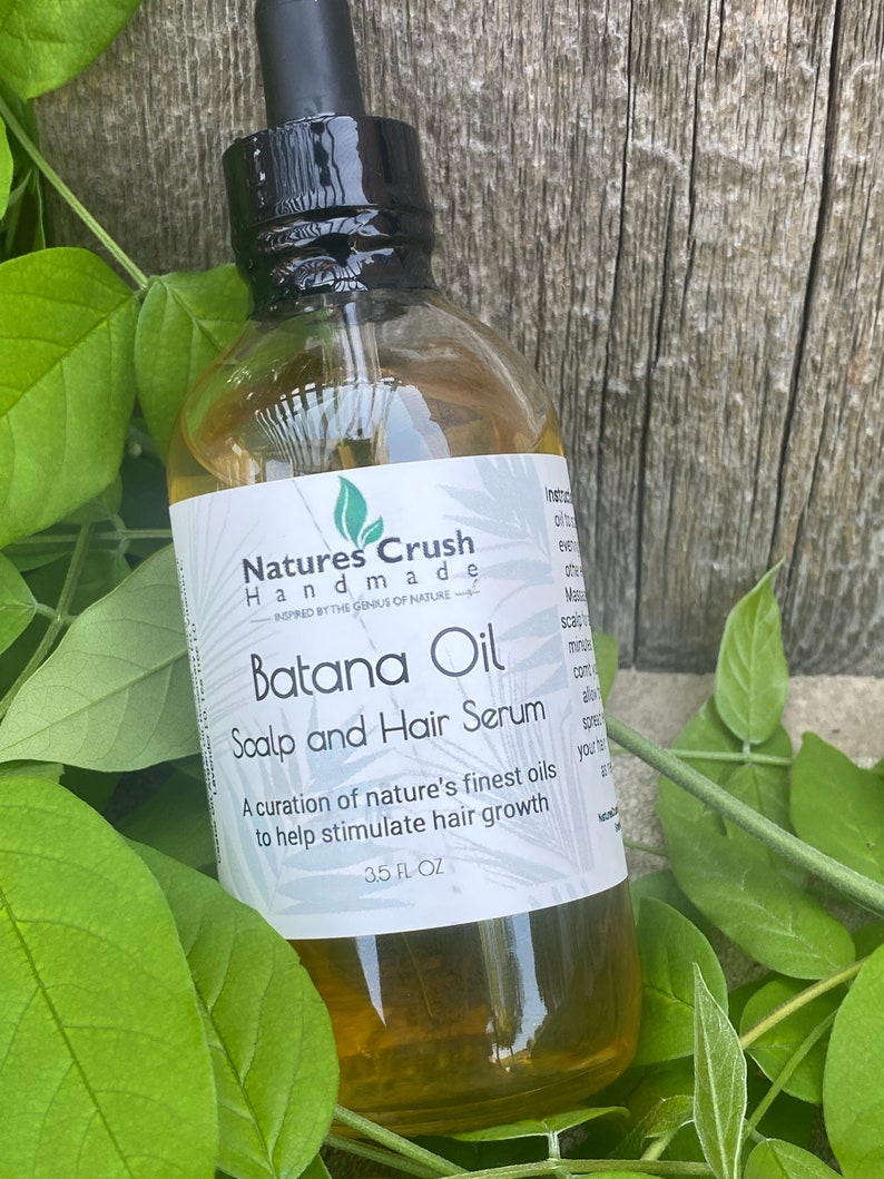 May include: A clear glass bottle with a black dropper top, containing a yellow liquid. The label reads "Natures Crush Handmade Inspired by the Genius of Nature Batana Oil Scalp and Hair Serum A curation of nature's finest oils to help stimulate hair growth 3.5 FL OZ".