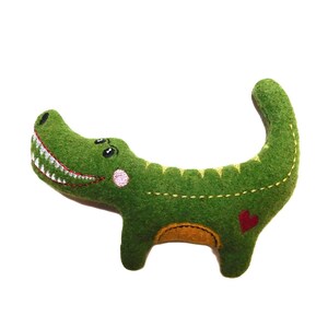 May include: Green felt crocodile plush toy with embroidered eyes, a pink cheek, and a red heart on its belly.
