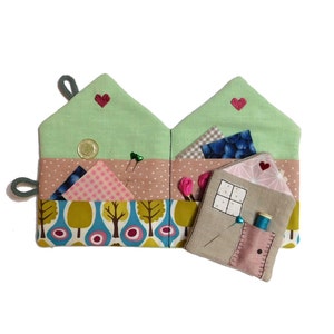 Könnte beinhalten: Ein grünes Stoff-Nähkästchen in Hausform mit einem rosa-weiß karierten Stoff, einem blauen Stoff mit weißen Punkten und einer kleinen hausförmigen Stofftasche mit einem Fenster und einem roten Herzen.