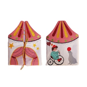 May include: Two white fabric pouches with embroidered circus designs. One pouch features a pink and red striped tent with yellow stars. The other pouch features a clown riding a unicycle with a seal balancing a red ball on its nose.