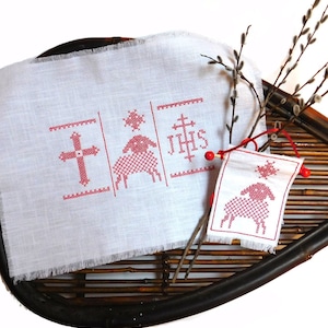 May include: White linen fabric with red embroidered cross, lamb, and "IHHS" design. The fabric is displayed on a woven basket with willow branches.