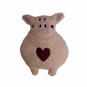 Op de afbeelding: Een roze pluche varkenspeelgoed met een rood hart op zijn borst. Het varken heeft een glimlachend gezicht met zwarte ogen en een roze neus.