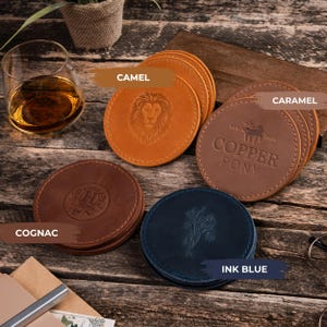 May include: A selection of round leather coasters in camel, caramel, cognac, and ink blue. Each coaster has embossed designs, including a lion, floral pattern, and the text "Copper Pony."