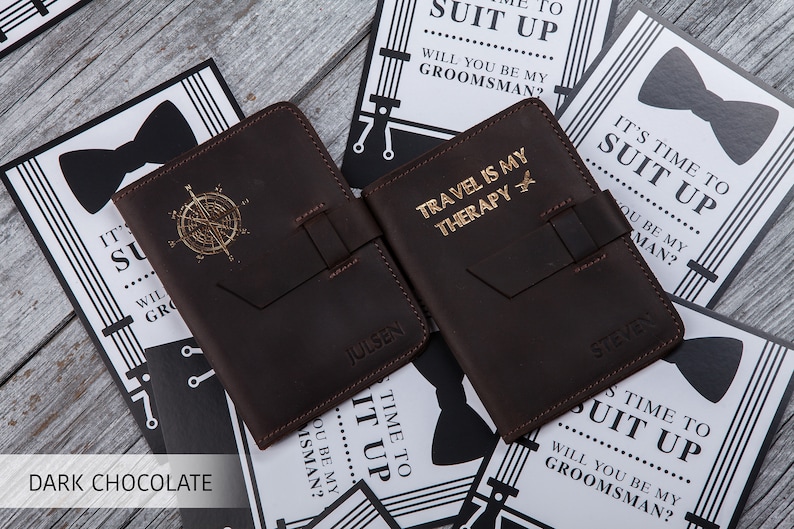 Puede incluir: Dos porta pasaportes de cuero marr&oacute;n chocolate oscuro con letras doradas. Un porta pasaportes dice "Travel is my therapy" con un peque&ntilde;o icono de avi&oacute;n. El otro porta pasaportes dice "Julsan".