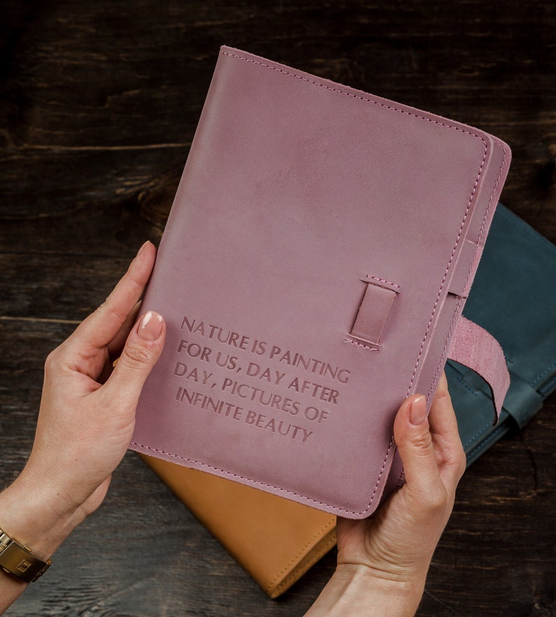 May include: A pink leather journal with the quote "Nature is painting for us, day after day, pictures of infinite beauty" embossed on the front cover.