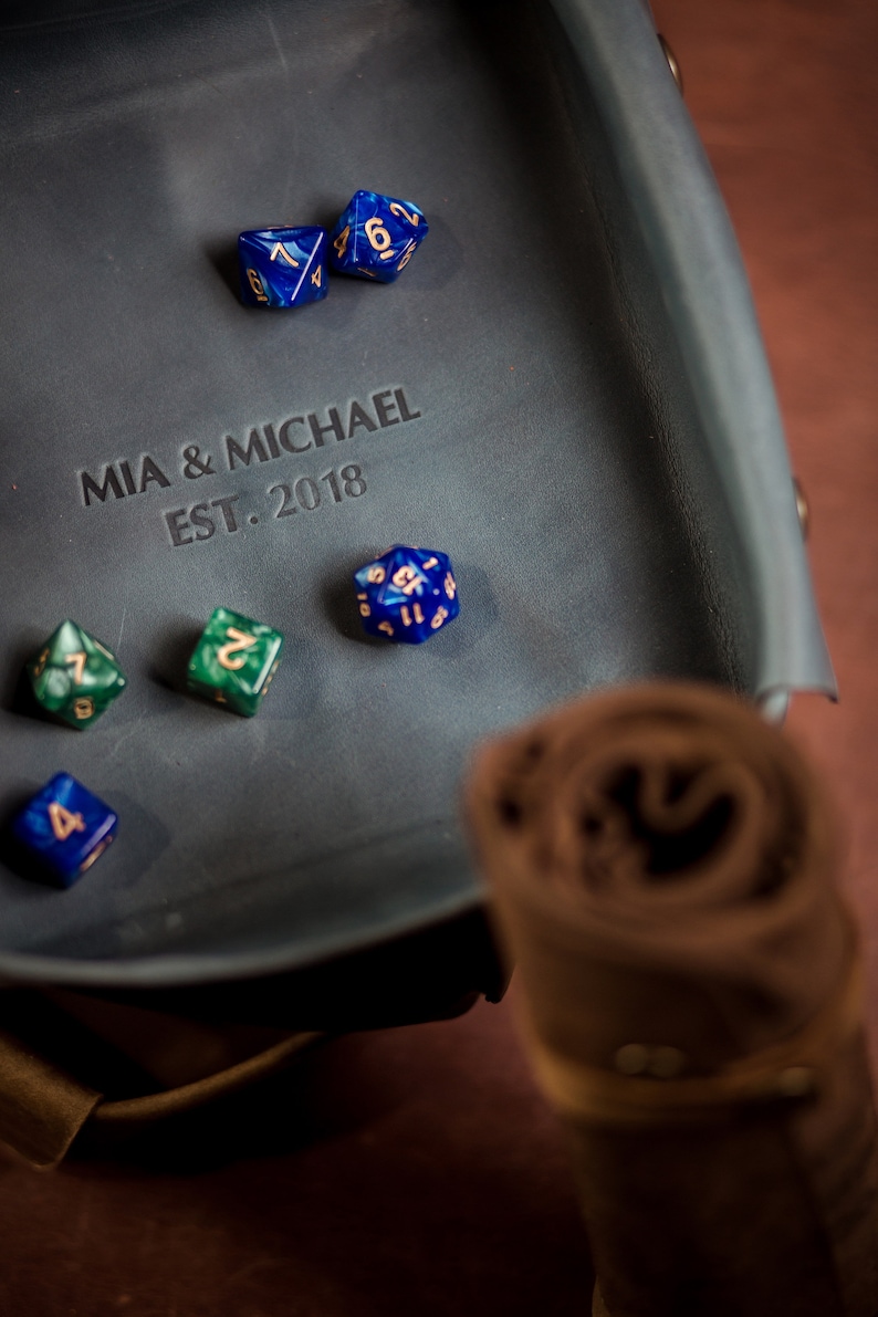 K&ouml;nnte beinhalten: Ein blaues Leder-W&uuml;rfeltablett mit der Aufschrift "MIA & MICHAEL EST. 2018" und mehreren blauen und gr&uuml;nen W&uuml;rfeln.