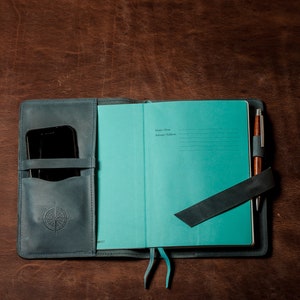 May include: A teal blue leather-bound journal with a pen and a phone holder. The journal has a section for "Name/Nom" and "Address/Adresse".
