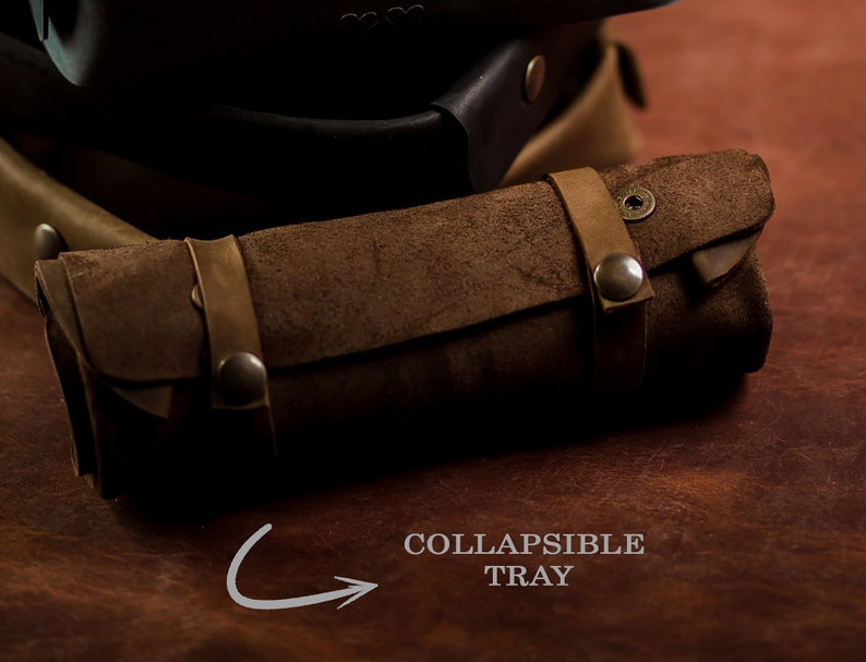 K&ouml;nnte beinhalten: Ein braunes Leder-Rolltablett mit Druckverschluss und Metall-Akzenten. Das Tablett ist mit "COLLAPSIBLE TRAY" beschriftet.