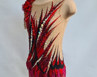 May include: A red and black leotard with a sheer fabric and a floral design on the shoulder. The leotard has a jagged hemline and is decorated with rhinestones.
