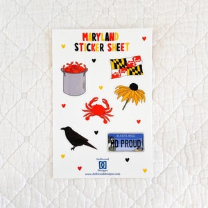 May include: A sticker sheet with a Maryland theme. The sheet includes a crab, a blackbird, a pot of crabs, a Maryland flag, a black-eyed Susan flower, and a Maryland license plate that says "Maryland So Proud".