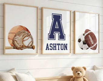 May include: Three framed wall art prints featuring sports themes. The left print shows a baseball and glove. The center print displays a large navy blue letter A above the name Ashton. The right print depicts a soccer ball and a football.
