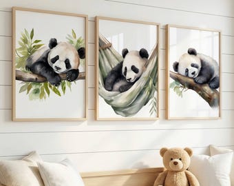 Op de afbeelding: Drie ingelijste wandkunstprints met aquarelillustraties van reuzenpanda's. De linkerprint toont een panda op een tak, het midden een panda in een hangmat en de rechter een slapende panda op een tak, allemaal in lichthouten lijsten.