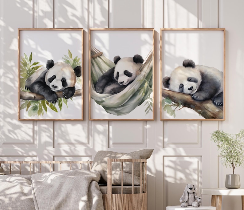 May include: Set of three framed watercolor prints featuring adorable panda bears. One panda rests on a branch, another in a hammock, and the third on a branch. The artwork has a soft color palette with green foliage and wooden frames.