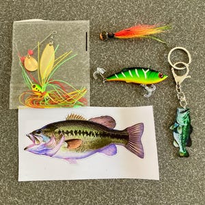 May include: A fishing lure kit with a variety of lures, including a green and yellow spinnerbait, a green and white crankbait, and a green and black bass lure. The kit also includes a sticker of a bass fish.