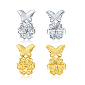 May include: Four earring backs, two in silver and two in gold. Each back features a butterfly design with a flower-shaped base with heart-shaped petals.