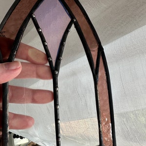 May include: A stained glass window panel with a gothic arch design. The panel features a purple glass center with a diamond shape and a copper foil border.