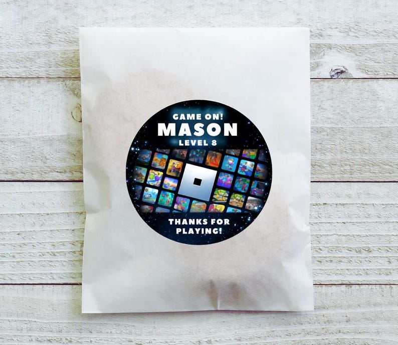 May include: A white paper bag with a circular sticker featuring the text "GAME ON! MASON LEVEL 8" in white. The sticker has a black background with a grid of colorful game images and the words "THANKS FOR PLAYING!"
