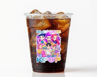 May include: A clear plastic cup filled with cola and ice cubes. A colorful sticker on the cup features a group of cartoon characters and the words "DEMON HUNTERS" and "KPOP". The drink is set against a white background.
