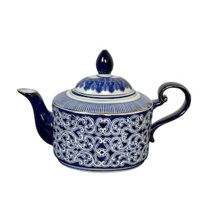 Peut inclure: Une théière en porcelaine bleue et blanche avec un couvercle et une anse. La théière présente un motif orné et détaillé en blanc sur un fond bleu foncé. Le couvercle a un petit bouton bleu foncé. Le bec et la anse sont également bleu foncé.