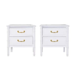 May include: Two white nightstands with two drawers each, featuring gold-colored handles. The nightstands have a bamboo-style design and are set against a white background. Each nightstand has a rectangular top.