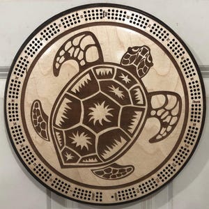 May include: A wooden game board with a brown turtle design. The board has a circular shape and is marked with numbers from 1 to 120. The board also has the words "Start", "Finish", and "Skunk" printed on it.