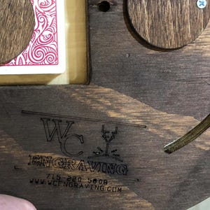 May include: A close-up of a wooden sign with the text "WC Engraving" and the phone number "715-220-5808" and the website "www.wcengraving.com".