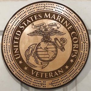 May include: A wooden cribbage board with a United States Marine Corps logo and the words "Semper Fidelis" and "Veteran".