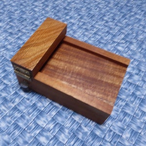 May include: A wooden box with a hinged lid. The lid is open and the box is made of a light brown wood.
