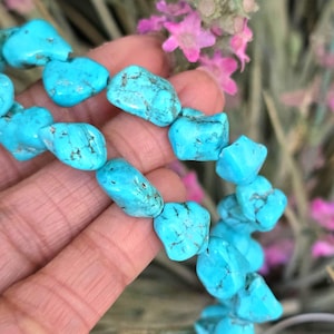 May include: A strand of turquoise gemstone beads, each bead is a unique, irregular shape with a light blue color and dark blue veining.