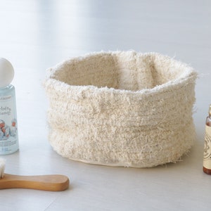May include: A white woven basket, a blue bottle of baby lotion with the text "Beb&eacute;s & Mamig" on the label, a wooden brush with white bristles, and two small brown glass bottles with gold lids.