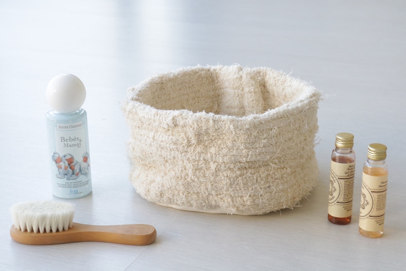 May include: A white woven basket, a blue bottle of baby lotion with the text "Beb&eacute;s & Mamig" on the label, a wooden brush with white bristles, and two small brown glass bottles with gold lids.