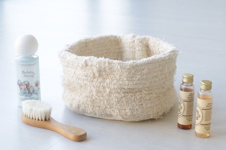 May include: A white woven basket with a white brush, a bottle of baby wash labeled "Beb&eacute;s & Mam&aacute;", and two bottles of brown liquid.