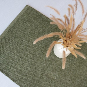 Peut inclure: Un tapis vert avec un vase blanc rempli d'herbe de la pampa séchée.