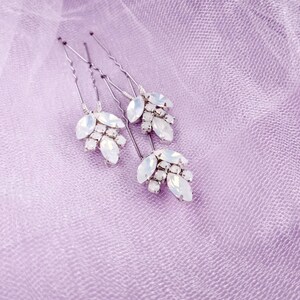 May include: Set of four silver hair pins with white opal-like stones arranged in a leaf design.