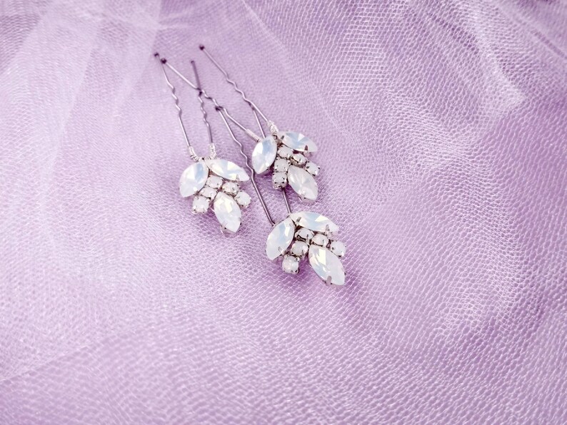 May include: Set of four silver hair pins with white opal-like stones arranged in a leaf design.