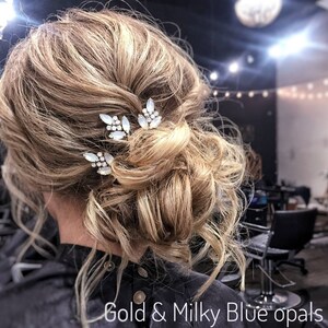 May include: A woman with blonde hair styled in a messy bun with three gold hair clips with milky blue opals. The hair clips are in the shape of leaves. The text "Gold & Milky Blue opals" is at the bottom of the image.
