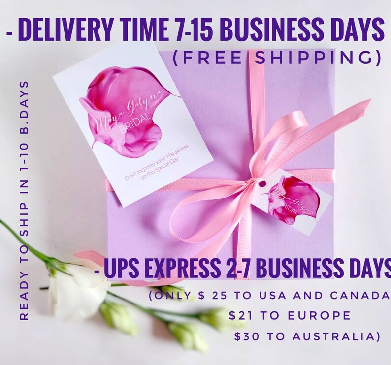 May include: A pink gift box tied with a pink ribbon. The box is wrapped in a light purple paper with a white tag that says "Maya Galyne Bridal" and "Don't forget to wear Happiness on this Special Day". The box is sitting on a white surface with a white flower.