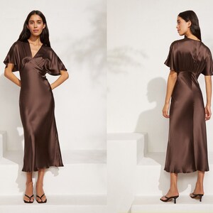May include: A brown satin midi dress with a V-neckline and short sleeves. The dress has a wrap-style bodice and a flowing skirt.
