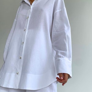 Pode incluir: Um conjunto de camisa e cal&ccedil;&otilde;es de linho branco. A camisa tem um colarinho cl&aacute;ssico e mangas compridas com punhos abotoados. Os cal&ccedil;&otilde;es s&atilde;o de corte largo com perna larga.