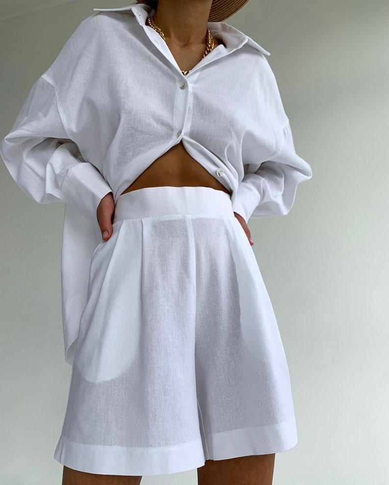 Pode incluir: Uma camisa branca de linho com mangas compridas e um par de cal&ccedil;&otilde;es brancos de linho. A camisa est&aacute; desabotoada e amarrada na cintura.