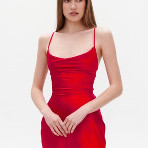 Puede incluir: Una mujer con un vestido de sat&eacute;n rojo con cuello de pico.